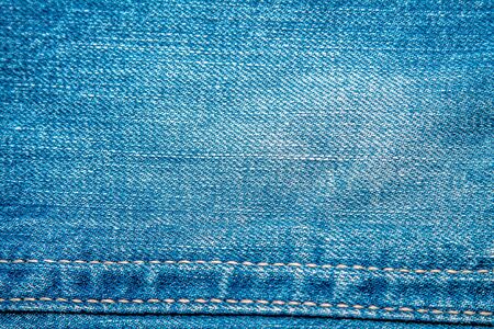 Jeans background. Denim fabric closeup. Textures of clothing fabric with fashion embroidery blue...