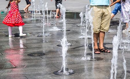 Residents and children splash in the city fountainの写真素材