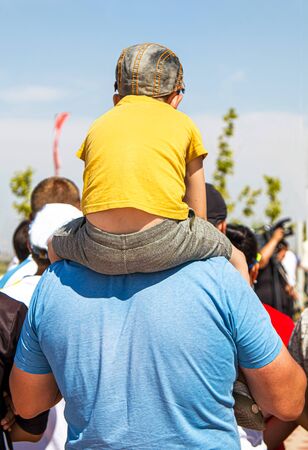 The child sits on the shoulders of a parent in the parkの写真素材