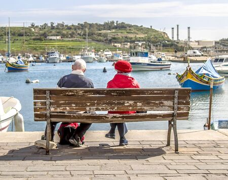Couple of pensioners on a bench by the sea in Maltaの写真素材