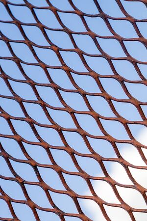 Metal grid on a background of blue sky as a background for designの写真素材