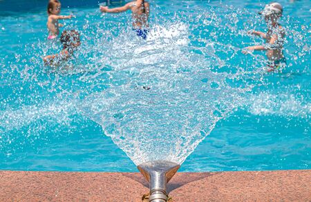 Fountain in the pool close-up. Children in the pool under water drops. Resort relaxation.の写真素材