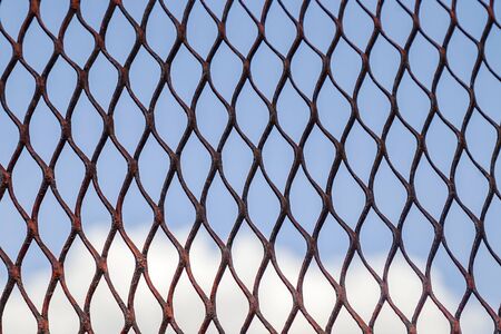 Metal grid on a background of blue sky as a background for design