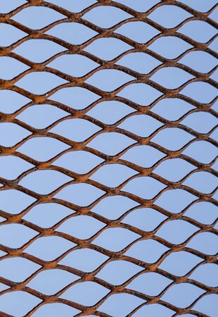 Metal grid on a background of blue sky as a background for designの写真素材