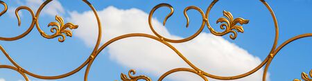Painted gold paint forged metal products against the sky as a background for designの写真素材