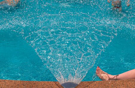 Fountain in the pool close-up. Children in the pool under water drops. Resort relaxation.の写真素材