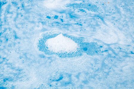 Soap foam on the water in the pool as an abstract background. Blur