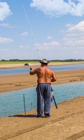 Elderly tanned fisherman by the riverの写真素材