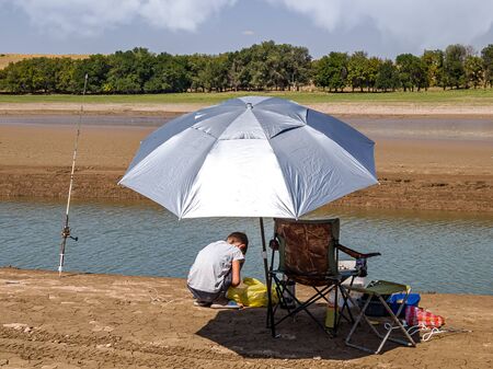 Fishing rods and umbrella by the river landscapeの写真素材