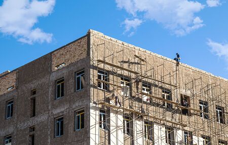 Building under construction in scaffolding against the skyの写真素材