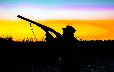 Silhouette of a hunter with a gun on a sunset backgroundの写真素材