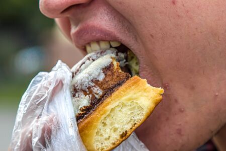 Man bites a sweet bun close-upの写真素材