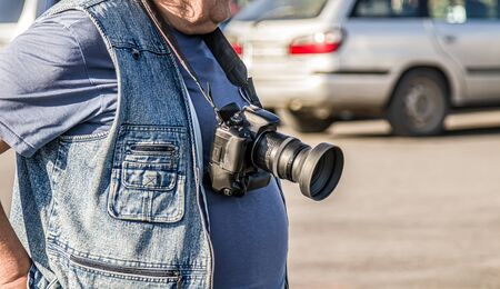 Close-up professional camera on the belly of a photographer