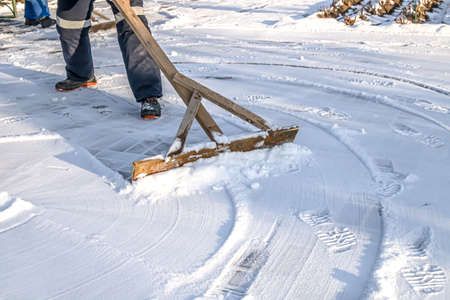 People clean the road from snow with hand tools.の写真素材