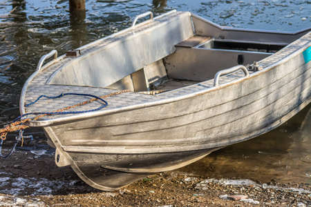A metal boat on the shore of a freezing lake.の写真素材