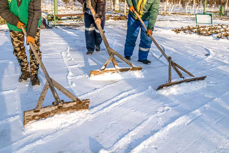 People clean the road from snow with hand tools.の写真素材