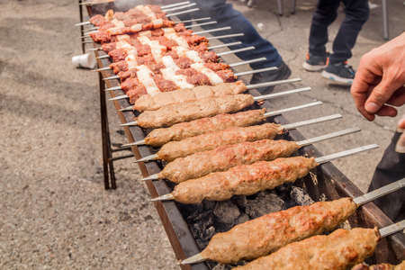 The meat is fried on skewers on the coals.Cooking delicious barbecue on the grillの写真素材