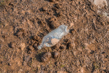 Dirty plastic bottle trash in mud.Ecological disaster concept.の写真素材