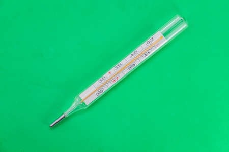 Mercury medical thermometer close-up on a green surfaceの写真素材