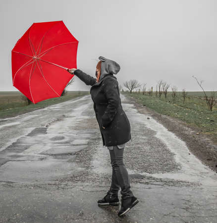 Girl holding an umbrella in windy weatherの写真素材