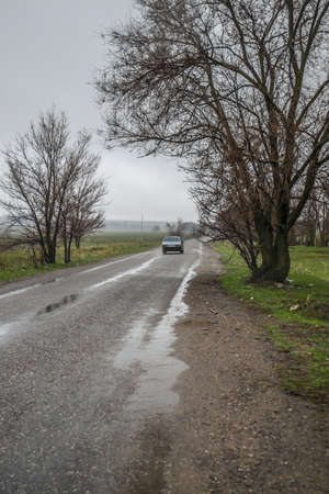 Lonely car on a country road in rainy weatherの写真素材
