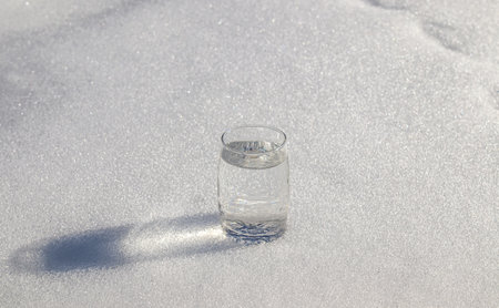 Glass cup with cold water on white snow.の写真素材