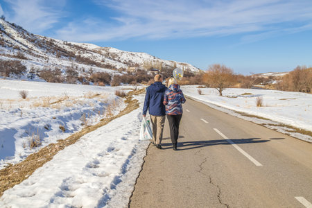 Loving couple walks along a mountain road rear view.の写真素材