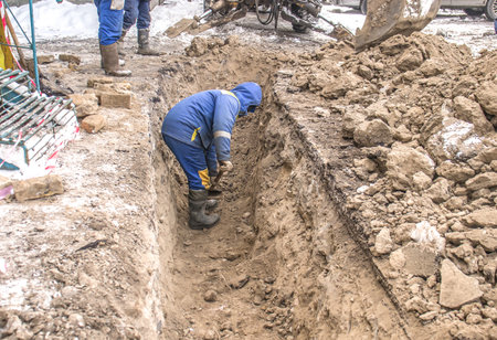 Digging trenches in winter in the city by hand with a shovel.の写真素材
