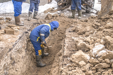 Digging trenches in winter in the city by hand with a shovel.の写真素材