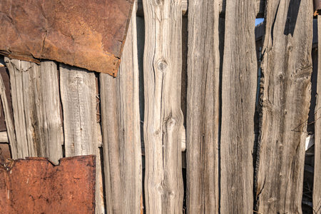 A fence made of old rotten boards close-up.の写真素材