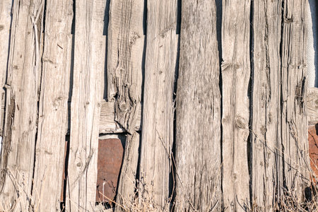 A fence made of old rotten boards close-up.の写真素材