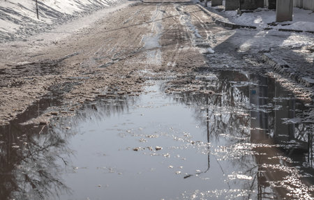 Muddy puddle on the road from melting snowの写真素材