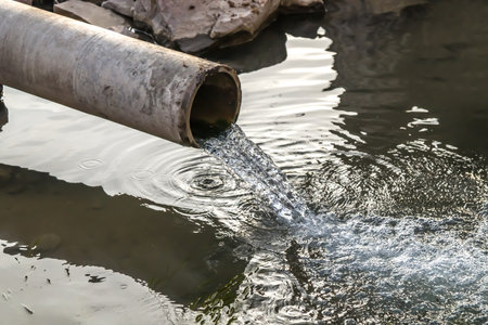 Sewer drains from a pipe into a river in the cityの写真素材