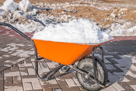 Snow is taken out on a hand wheelbarrowの写真素材