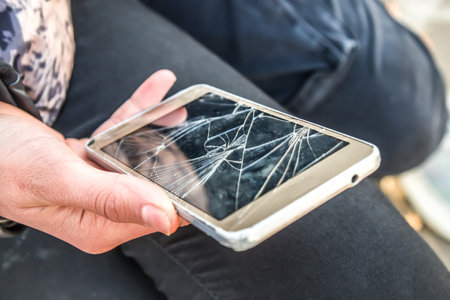 Cell phone with broken screen in handの写真素材