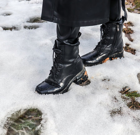 A girl in dirty shoes walks through the melting snowの写真素材