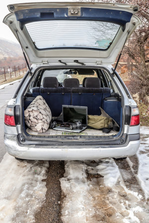 Travel by car. Camera and laptop in the open trunk of a carの写真素材