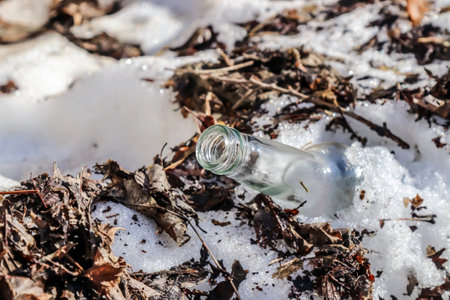garbage from glass bottles in the snow in winter.mud from under the melting snow in springの写真素材