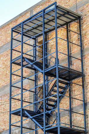 Steel structure fire escape on the brick wall of the building. Outdoor fire escapes installed outside. Facade with fire and rescue steel stairs.の写真素材