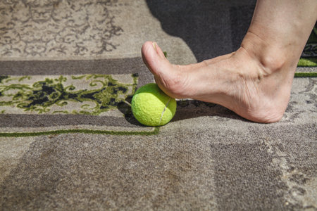 Massaging a person's foot with a tennis ball