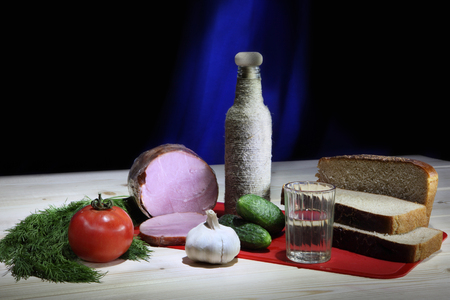 Still life with bread, ham, vegetables and bottle of vodkaの写真素材
