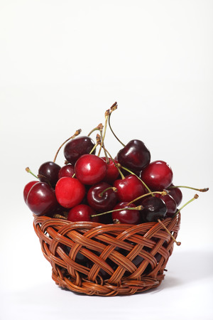 Wicker basket with ripe cherries on white backgroundの写真素材