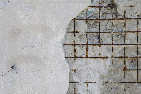 On the old wall part of the plaster fell off and a rusty metal grid is visible. Background for your designの写真素材