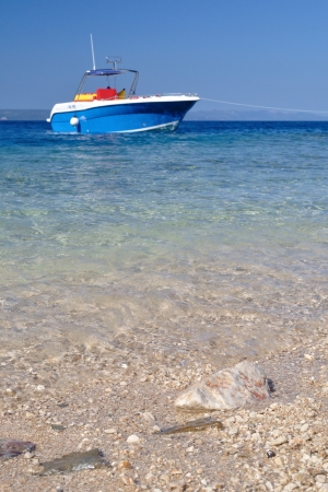 Beach of Podgora with some rocks in front and blue ship in backgroundの写真素材