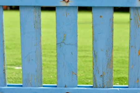 Blue wooden picket fence with blurred green backgroundの写真素材
