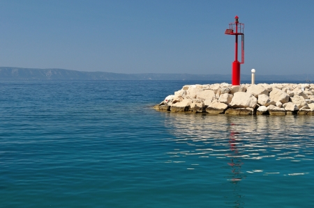 Red lighthouse in port with stones  Tucepi, Croatia  Space in left side の写真素材
