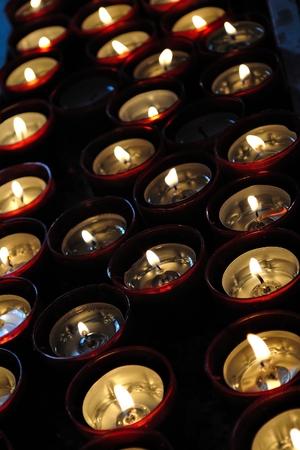 Burning tea lights on black background  Vertical photoの写真素材