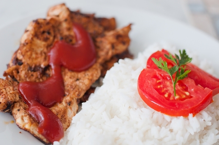 Chicken steak in a dish served with rice and tomato sliceの写真素材