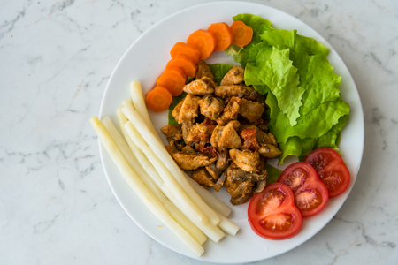 Fried chicken meat served on plate with white asparagus, carrot, tomato and lettuce. Top viewの写真素材