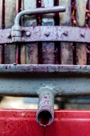 Wooden wine press with red must for pressing grapes to produce wine. Traditional old technique of wine-making. Vertical photoの写真素材